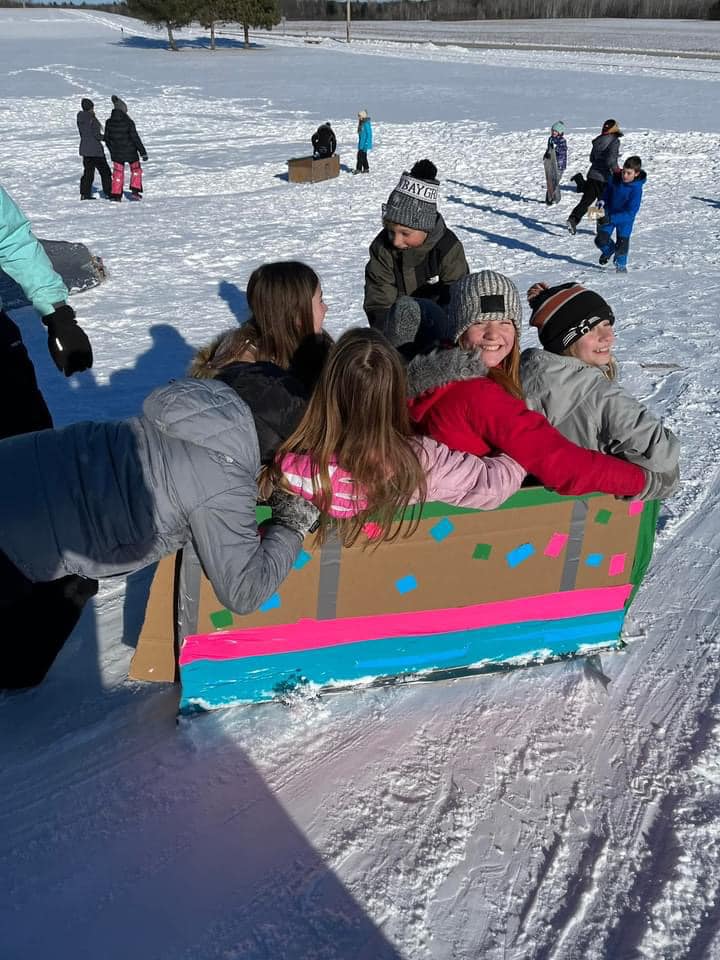 kids sitting in a home made sled in the snow